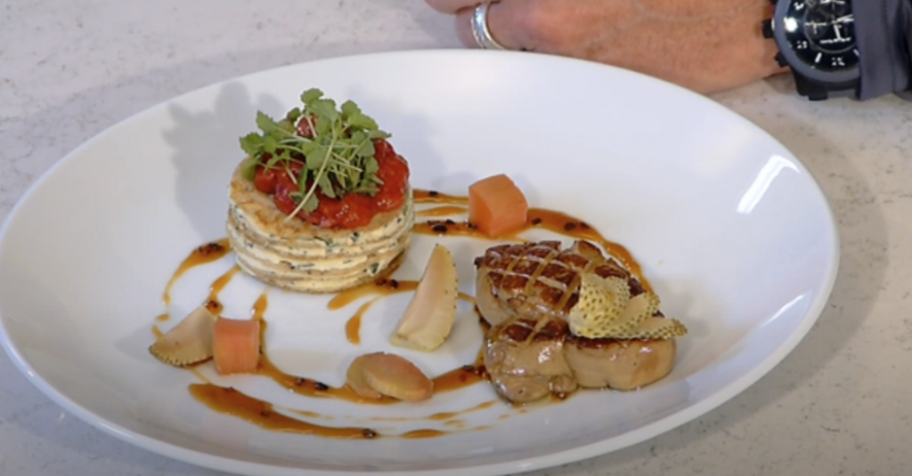 Photo of a beautifully arranged dish on a large plate, featuring pancakes and meat