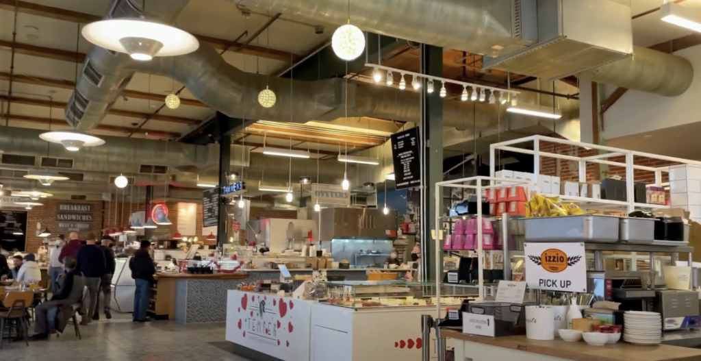 Photo of the interior of a building with a variety of food stalls